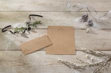Stationery and envelope on wooden table, decorated with fir branches, cones and ribbon