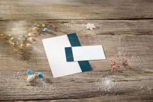 Stationery and envelope on wooden table, decorated with fairy lights and winter accessories