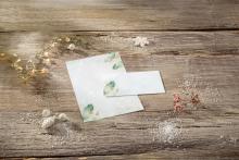 Paper with plant motif on wooden table, surrounded by fairy lights and decoration