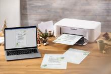 Laptop and printer on wooden table, printouts