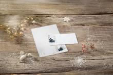 Stationery with winter motif, on wooden table with decorative branches and snow glitter
