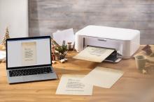 Laptop and printer on table, print holiday letter