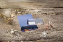 Christmas cards on wooden table surrounded by fairy lights and decorations