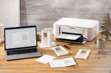 Laptop and printer on table Christmas cards are printed