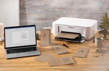 Laptop, printer and Christmas cards on wooden table