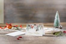 Christmas card with fir branches and text Merry Christmas on wooden table In the background a small Christmas tree