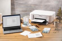Laptop and printer on wooden table with Christmas cards