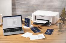 Laptop and printer on wooden table with Christmas cards