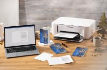 Laptop and printer on a table, Christmas cards are printed