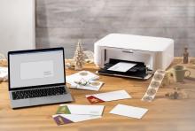 Laptop and printer on wooden desk with Christmas cards