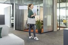 Person im Büro mit Tasche und Getränk