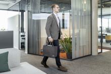 Person in Büro, trägt Anzug und Tasche