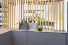 Graue und schwarze Filztaschen auf Schrank, daneben Pflanze