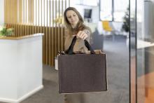 Person hält schwarze Stofftasche in einem Büro