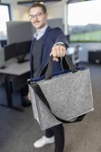 Person im Büro mit grauer Tasche