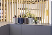 Vier Filztaschen auf einem Tisch vor Holzlamellen und Pflanzen