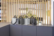 Fünf Stofftaschen auf Tresen vor Holzpanel