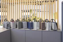 Mehrere bunte Filztaschen vor Holzstreben