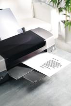 Printer on table, paper with text is output sofa and plant in background
