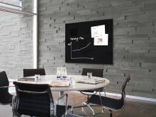 Konferenzraum mit Tisch, Stühlen und Wandtafel mit Grafiken