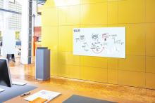 Whiteboard with sketches on yellow wall in modern office
