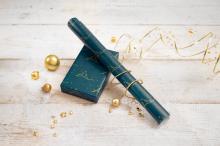 Dark blue wrapping paper, golden baubles and star decoration on light wooden table