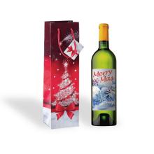 Wine bottle with festive label, next to red gift bag with snowflake tree and bow