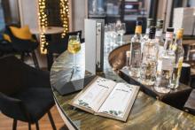 Drinks menu on a counter, cocktail glass and bottles in the background