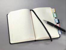 Notebook with tabs, ballpoint pen lies on it