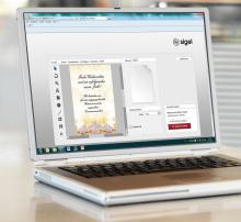 Laptop with open design program, showing Christmas card with text Merry Christmas and a prosperous new year!