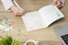 Personen schreiben in ein Heft, Geld liegt daneben