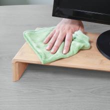 Hand wiping dust on wooden board with green cloth