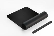 Schwarze Schreibtischunterlage, ausgerollt und gerollt, mit Halteriemen