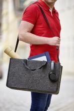 Mensch in rotem T-Shirt trägt eine graue Tasche mit Kopfhörern, Rollen und Ordnern