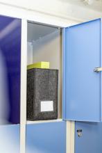 Offener blauer Spind mit schwarzem Ordner und gelber Box