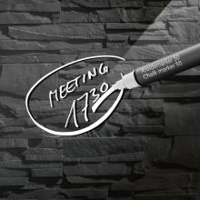 Meeting 17:30 written with chalk marker on black stone wall