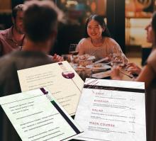 Menschen am Tisch mit Speisekarten; sie lachen und unterhalten sich