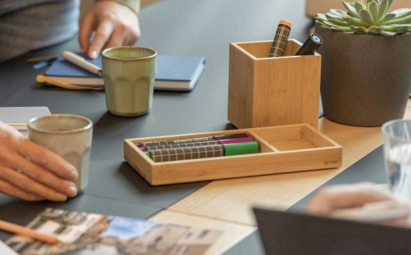 Eyestyle Zubehörablage und Stifteköcher auf Meetingtisch mit Händen von Kollegen