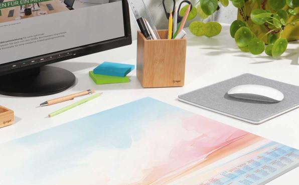 Papier-Schreibunterlage in Watercolor-Optik liegt auf Schreibtisch vor Monitor und neben Mauspad