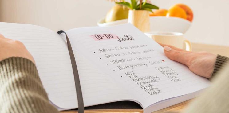 Frau liest Todo-Liste in Notizbuch