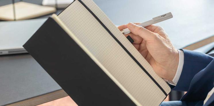 Mann schreibt in offenes Notizbuch