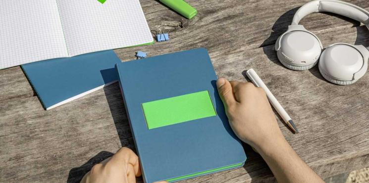 Linescape Neo Notizbuch in blau, neben Kopfhörer, Kugelschreiber und Farbstift