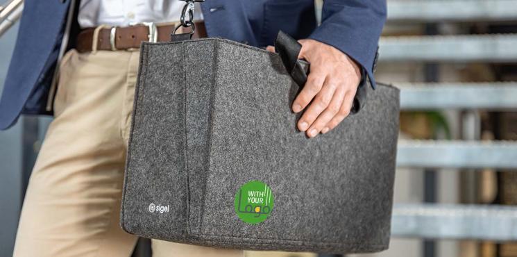 Ein Mann trägt eine dunkelgraue Filz-Businesstasche mit Logoaufdruck über der Schulter