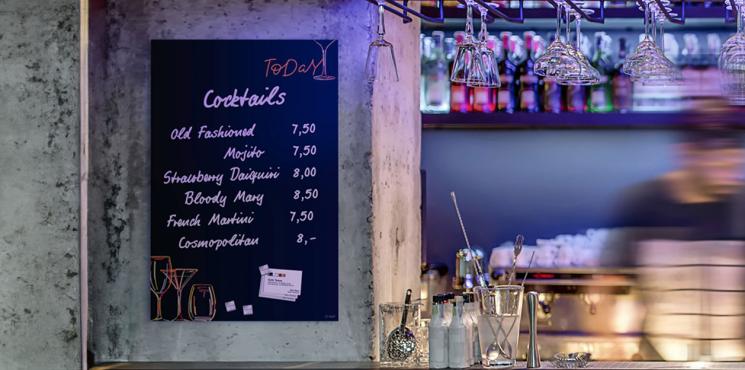 Glas-Magnettafel mit Cocktailkarte hängt an der Wand in einer Bar
