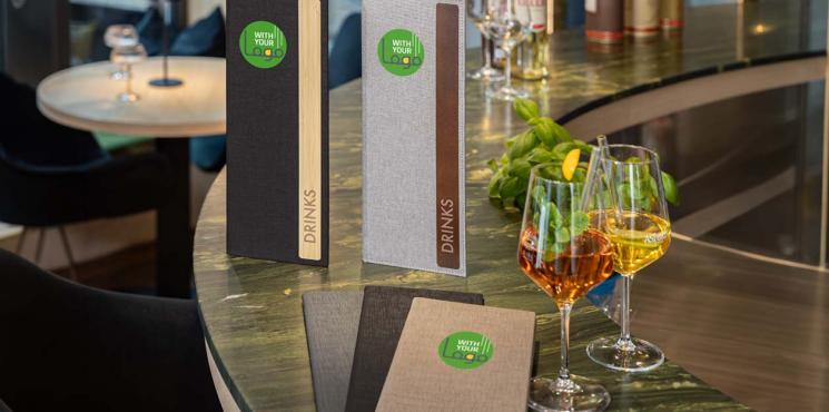 Auf einer Bartheke stehen unterschiedliche Getränkekarten von SIGEL