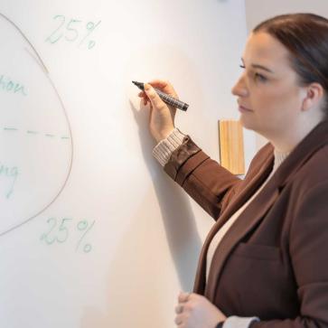 Frau schreibt mit Stift an Whiteboard