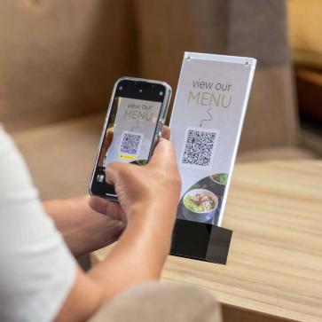 Mann scannt QR-Code im Restaurant mit Smartphone